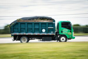 pexels photo 11521609 11521609 A green truck transporting yard waste on a road captured in motion. Perfect for transportation and environmental themes.