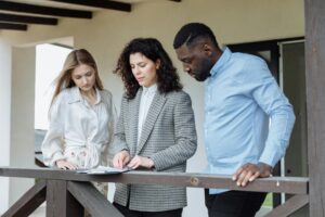 pexels photo 8470794 8470794 Three adults reviewing documents on a balcony during a real estate consultation.