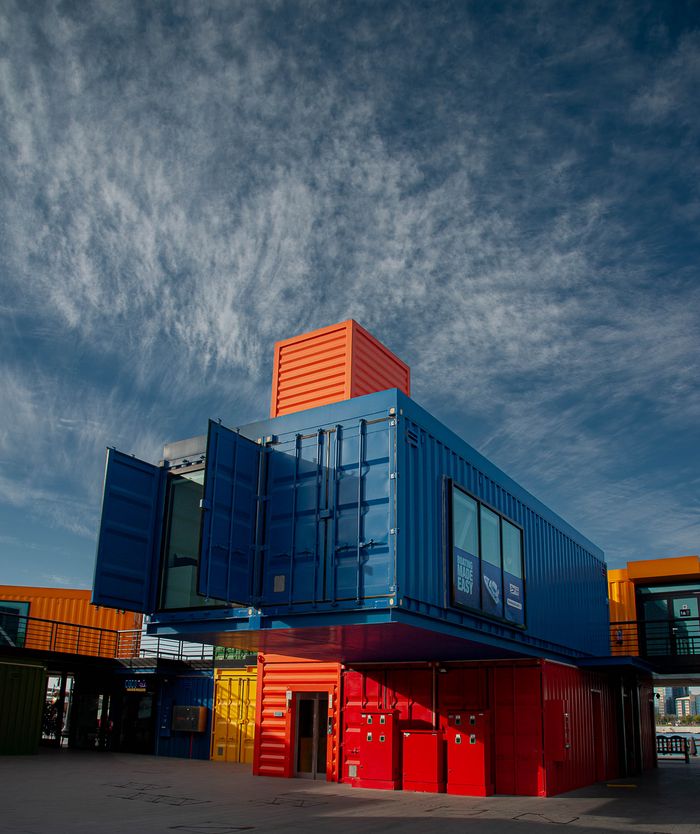 Our Services Vibrant shipping containers arranged creatively under a bright sky, showcasing modern architectural innovation.